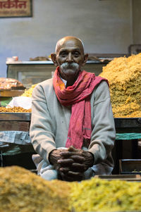 Portrait of man sitting at market stall