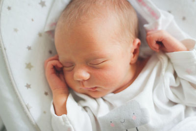 Gentle innocent newborn baby sleeps on light baby cocoon, closeup portrait at home