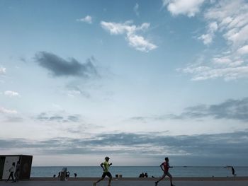 People standing on beach against sky