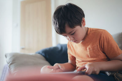 Boy using digital tablet while sitting at home