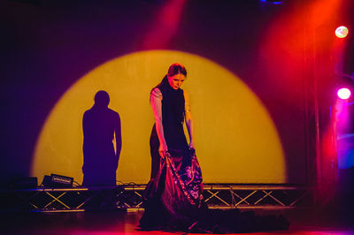 Portrait of woman standing against yellow light