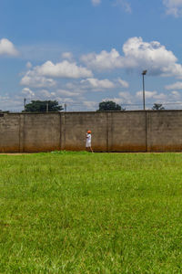 Side view of man standing on field against sky