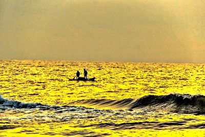 Silhouette person on sea against sky during sunset