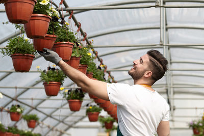 Side view of young man standing in potted plant