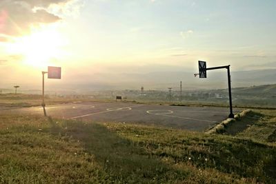 Basketball hoop on field against sky during sunset