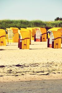 Hooded chairs at beach against clear sky