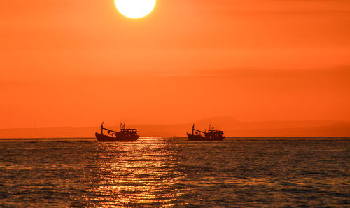 Two fishing boats against sunset