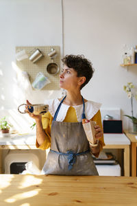 Coffee break in studio. woman potter drink tea from handicraft mug in creative ceramic art workshop