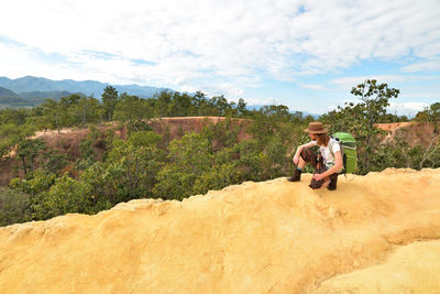 Man sitting on land against sky