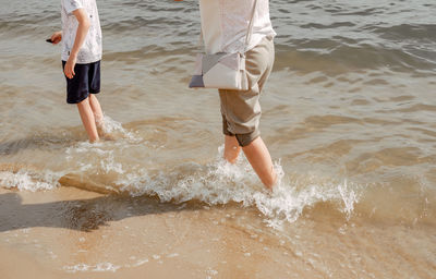 Mother and child walking on a sandy beach. cool water in the sea. walk along the beach barefoot. 