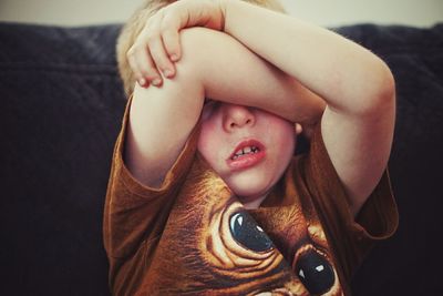 Boy covering face at home