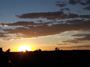 Scenic view of silhouette field against sky during sunset