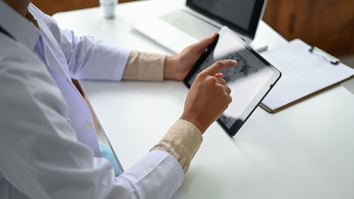 Midsection of man using laptop on table