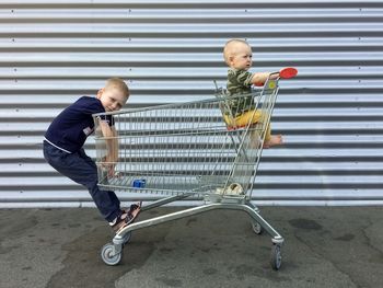 Boys in a grocery cart on a metal background