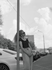 Woman standing by car against sky