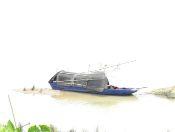 Boats moored on shore against clear sky