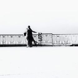 Woman standing on bridge against clear sky