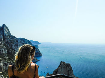 Woman looking at sea against clear sky