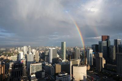 Panoramic view of rainbow over buildings in city against sky