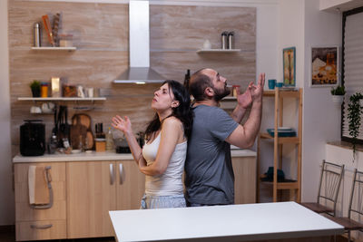Couple arguing while standing in kitchen at home