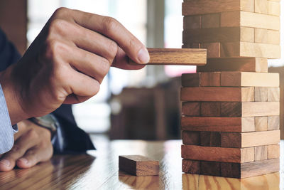 Cropped hands of man playing block removal game on table