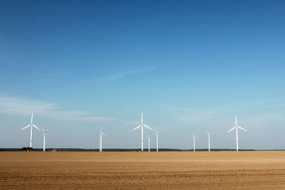 Wind turbines on field against sky