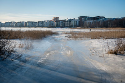 Scenic view of frozen river against cityscape during winter