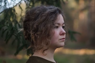 Close-up of young woman against trees