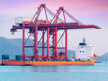 Cranes at pier against sky