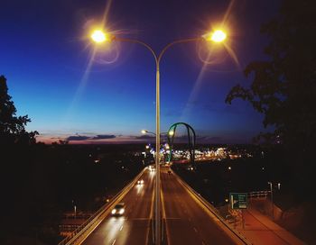 Illuminated street lights on road in city at night