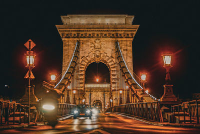 Illuminated bridge over river at night