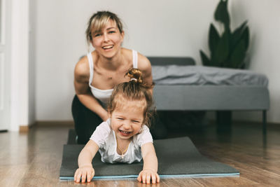 A young mother and her little daughter have fun on the mat before playing sports