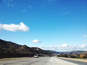 Road by mountain against blue sky