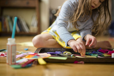 Close up view of a small child making art on floor in window light