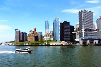 Boat sailing in east river by cityscape against sky