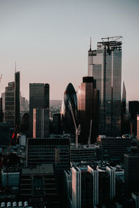 Modern buildings in city against sky during sunset