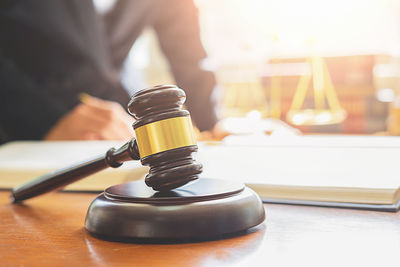 Close-up of gavel on table with female lawyer in background at office