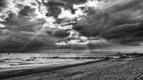 Scenic view of beach against cloudy sky