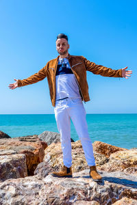 Full length of man standing by sea against blue sky