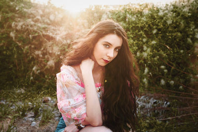 Portrait of beautiful young woman sitting on land