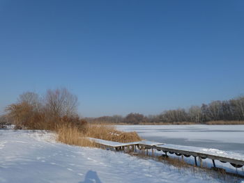 Snow covered field against sky during winter