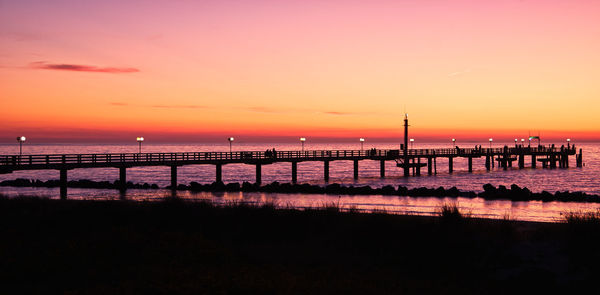 Silhouette pier over sea against sky during sunset