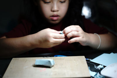 Close-up of girl holding hands craft toy on table