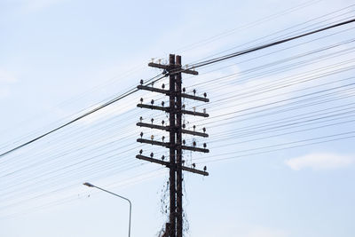 Low angle view of electricity tower against clear sky