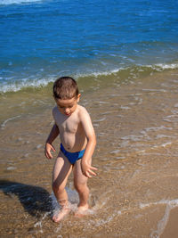 Young happy boy running on the beach during sunny summer day