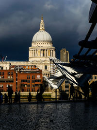 Buildings at waterfront against cloudy sky