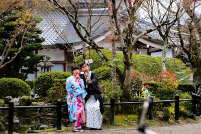 Happy woman with flowers on tree against built structure