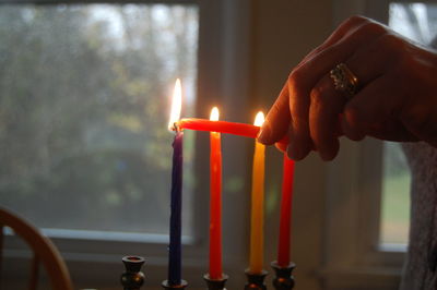 Cropped image of woman igniting candles on hanukkah at home