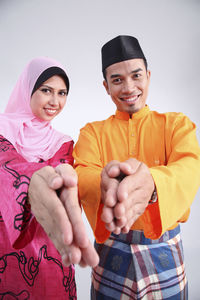 Portrait of happy couple in traditional clothing greeting against white background