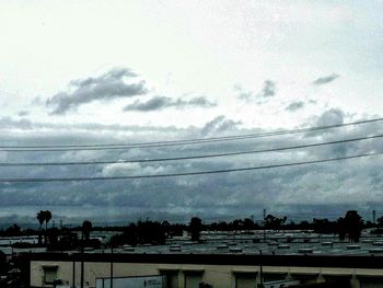 Power lines against cloudy sky